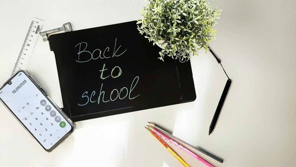 Top view of a back-to-school-themed workspace with stationery and plants.